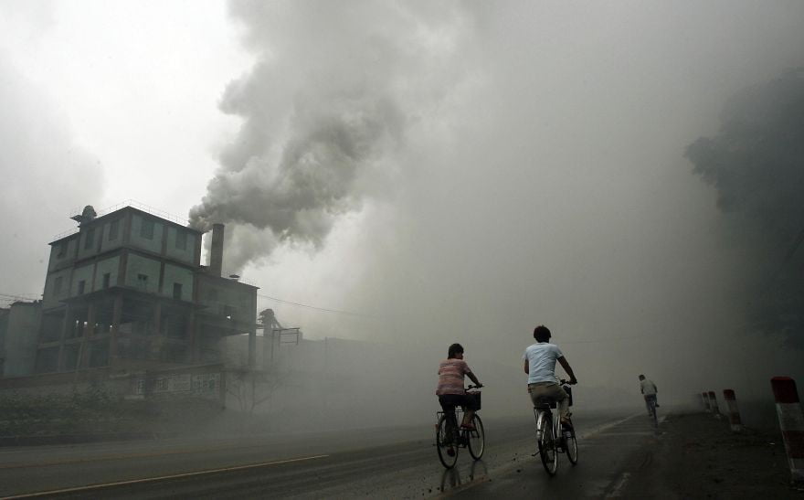 (FILES) - This photo taken on July 18, 2006 shows cyclists passing through thick pollution from a factory in Yutian, 100km east of Beijing in China's northwest Hebei province. Surging levels of carbon dioxide sent greenhouse gases in the atmosphere to a new record in 2013, while oceans, which absorb the emissions, have become more acidic than ever, the UN said on September 9, 2014. AFP PHOTO / PETER PARKS